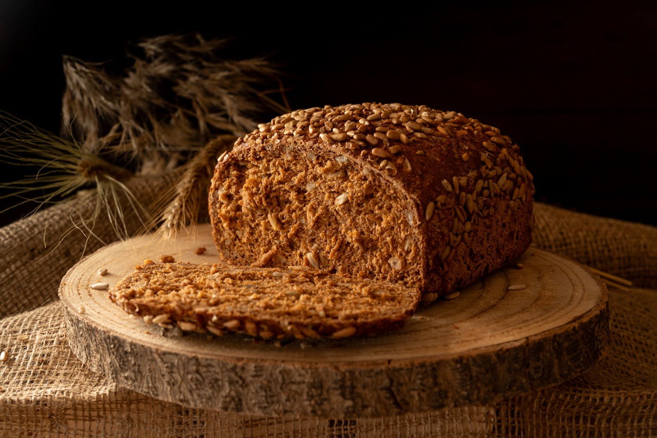 Wholegrain bread with sunflower seeds on a wooden board, representing foods that naturally contain gluten.